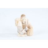 Japanese Meiji period carved ivory netsuke, in the form of a figure holding a fish and basket,