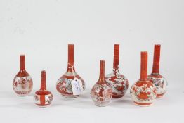Seven Japanese miniature bottle vases, to include one pair, all in iron red on a white ground with