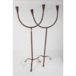 Pair of eastern metal floor standing candelabra, each having twin branches and raised on three feet,