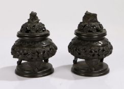 Two Japanese bronze pots and covers, with a dome top above the rounded squat body raised in legs, (