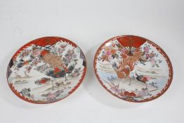 Two Japanese Kutani porcelain plates, each painted in iron red and gilt, depicting birds under a fan