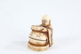 Japanese Meiji period carved ivory netsuke, in the form of a seated figure holding a dish, 3cm high