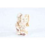 Japanese Meiji period carved ivory netsuke, in the form of a kneeling man holding a mask,