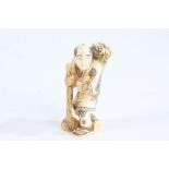 Japanese Meiji period carved ivory netsuke, in the form of a man with a basket of food over his