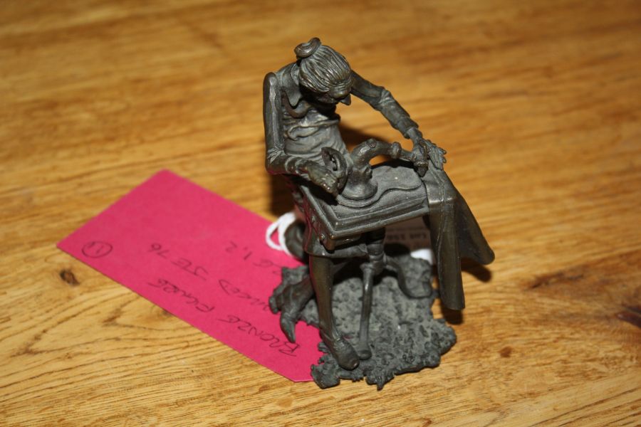 Spelter figure depicting an elderly lady on an early sewing machine. 10 cm tall, marked JE76.