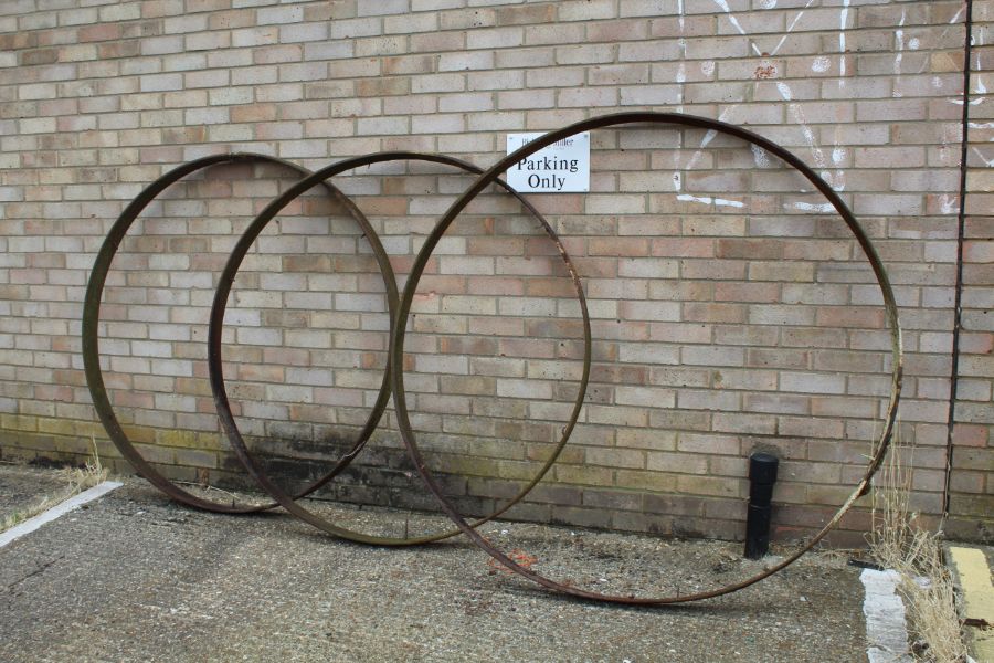 Three large cast iron wheel trims, approx. 141cm diameter and 159cm diameter (3)