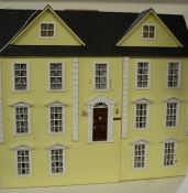 Large yellow painted wooden dolls house, 20th century, having hinged doors and roof with various