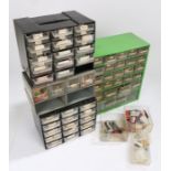 Four plastic and metal banks of workshop drawers, containing watch batteries, crowns, hands etc. (