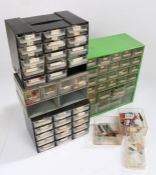 Four plastic and metal banks of workshop drawers, containing watch batteries, crowns, hands etc. (