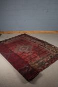Middle Eastern rug, the red ground decorated with three lozenges, surrounded by multiple borders and