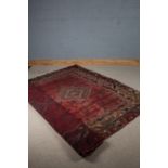 Middle Eastern rug, the red ground decorated with three lozenges, surrounded by multiple borders and