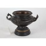 Bronze pedestal bowl, with beaded rim above a bulbous mask decorated twin handled body, raised on