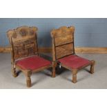 Pair of Rajasthani low chairs, with geometric and bird carved backs above over-stuffed seats, on