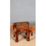 Eastern hardwood occasional table, the stepped square top above four carved elephant supports,