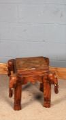 Eastern hardwood occasional table, the stepped square top above four carved elephant supports,