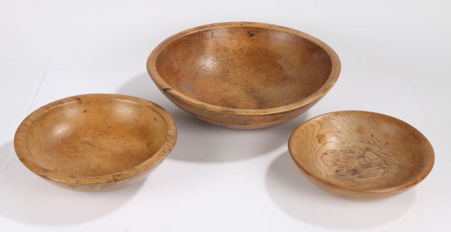 Three 19th Century treen dairy bowls, the largest example with a ring turned outside edge, 38cm