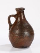 17th Century brown glazed bottle, with a wide lip above a bulbous body and arched handle, 19cm