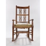 19th Century elm and ash rocking chair, with a spindle back above turned arms and a rush seat upon