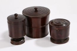 Three 19th Century hardwood treen storage jars, the first of tapering barrel form with an inset lid,