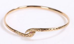 9 carat gold bangle in the form of a snake curled up with garnets for eyes, gross weight 6.0 grams