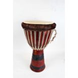 West African Djembe drum, the hollow hardwood base with coloured rope, 63cm high, 35cm diameter