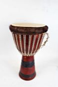 West African Djembe drum, the hollow hardwood base with coloured rope, 63cm high, 35cm diameter