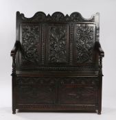 An oak settle, the arched and three carved panel back depicting a rose to the centre flanked by