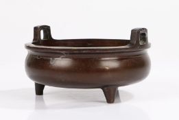 Chinese bronze censer, the raised angular handles above a flared rim, raised on three tapering feet,