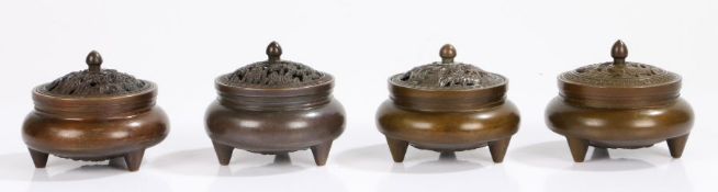 Four Chinese bronze censers, the pierced covers with depictions of foliage, fish and birds, above