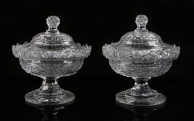 Pair of cut glass sweet meats, with angled finials above an oval lidded body and facetted stemmed