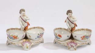 Pair of early 20th Century porcelain twin salts, surmounted by a standing putto above two foliate