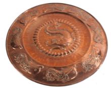 Cornish Arts and Crafts Hayle copper charger, decorated with a stylised repousse dolphin within a