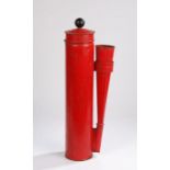 Red painted fire extinguisher, the ebonised pump handle above a cylindrical body flanked by a