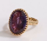 14 carat gold and amethyst set ring, the oval amethyst with facetted edge set to the woven effect