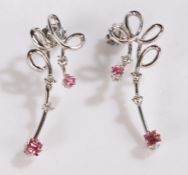 Pair of 18 carat white gold diamond and pink gemstone earrings, each with a swirl above the stone