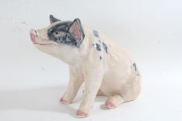 Large porcelain figure of a seated pig, 32cm high and 44cm long