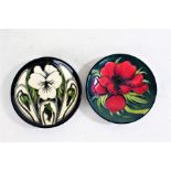 Two Moorcroft pin dishes, one with a red flower on a green ground, the other with white flowers on a
