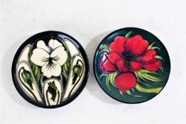 Two Moorcroft pin dishes, one with a red flower on a green ground, the other with white flowers on a