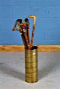 Brass embossed cylindrical stick stand, with contents of nine various walking sticks