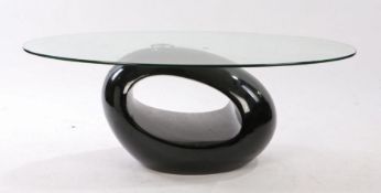 20th Century glass coffee table. the oval glass top above the black oval shaped base, 110cm long,