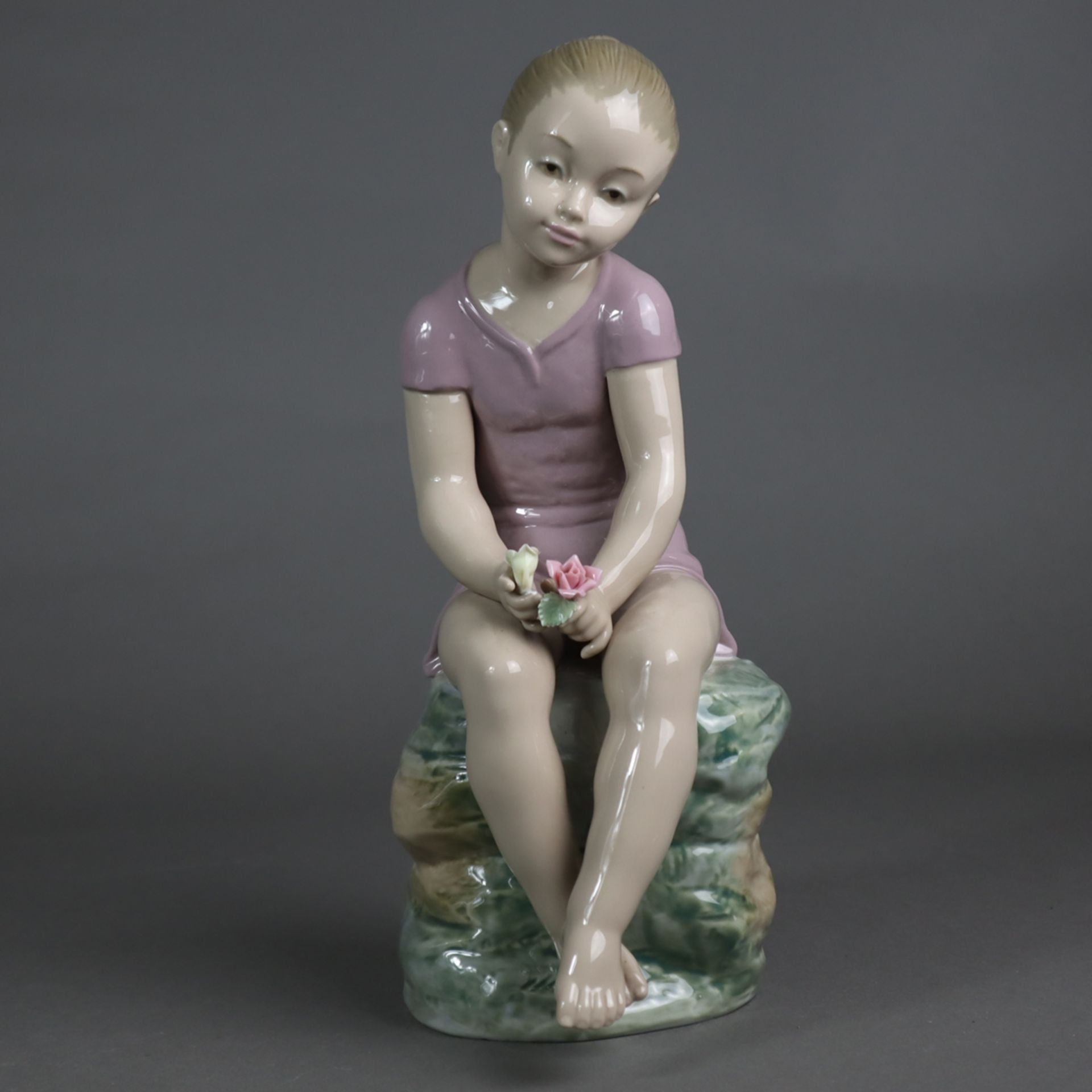 Porzellanfigur - Liebreizende Mädchenfigur, auf einem Steinquader sitzend, mit