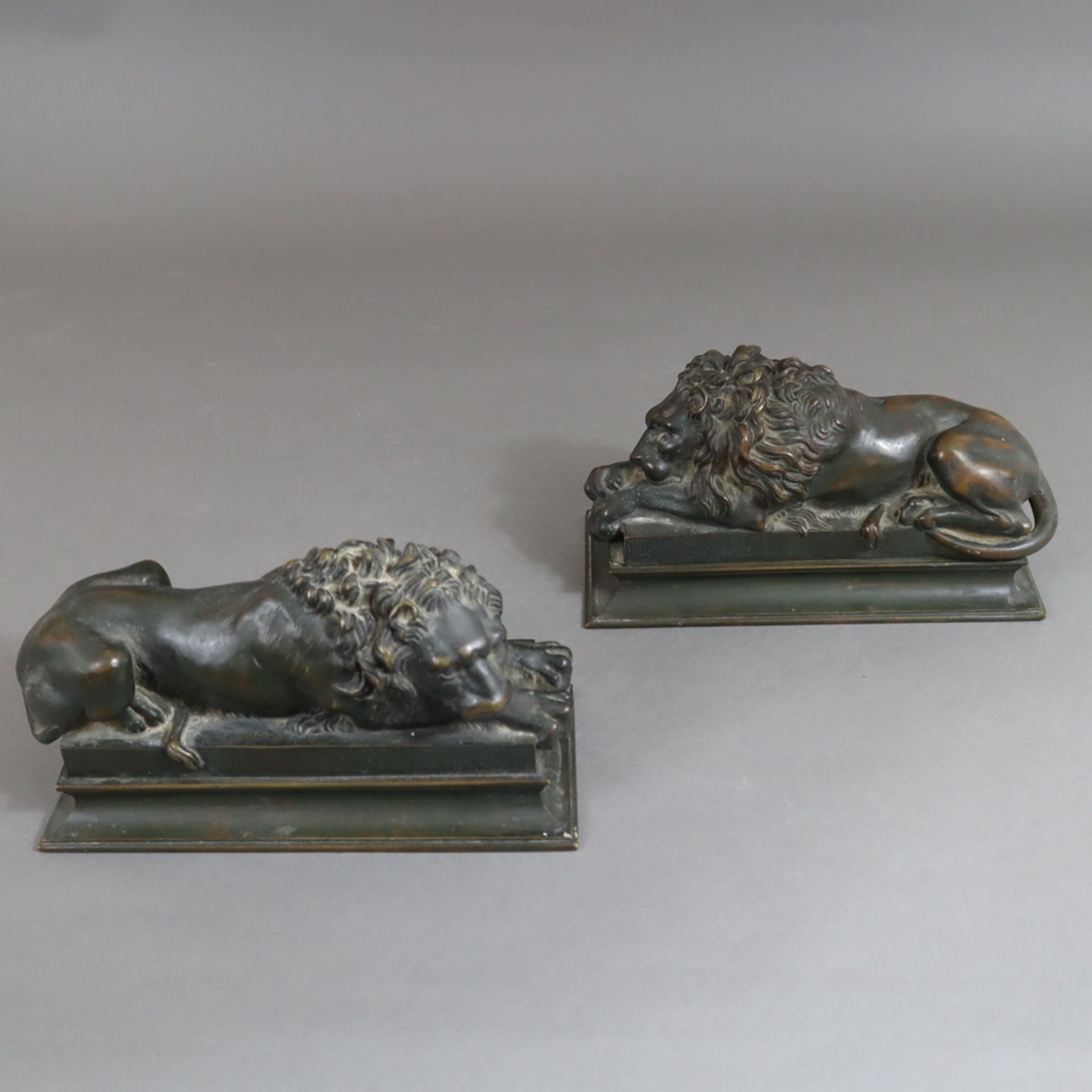 Paar Kaminböcke mit liegenden Löwen - Bronze, patiniert, auf gestuftem Sockel jeweils ein vollplast