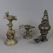 Drei Öllampen - Indien, Bronze, dunkel patiniert, 1x figürliche Öllampe, auf rundem Sockel stehende