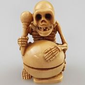 Netsuke - Elfenbein mit dunkler Patina, Japan, Meiji/Taisho-Zeit, Skelett mit Mokugyo (=Schlitztrom