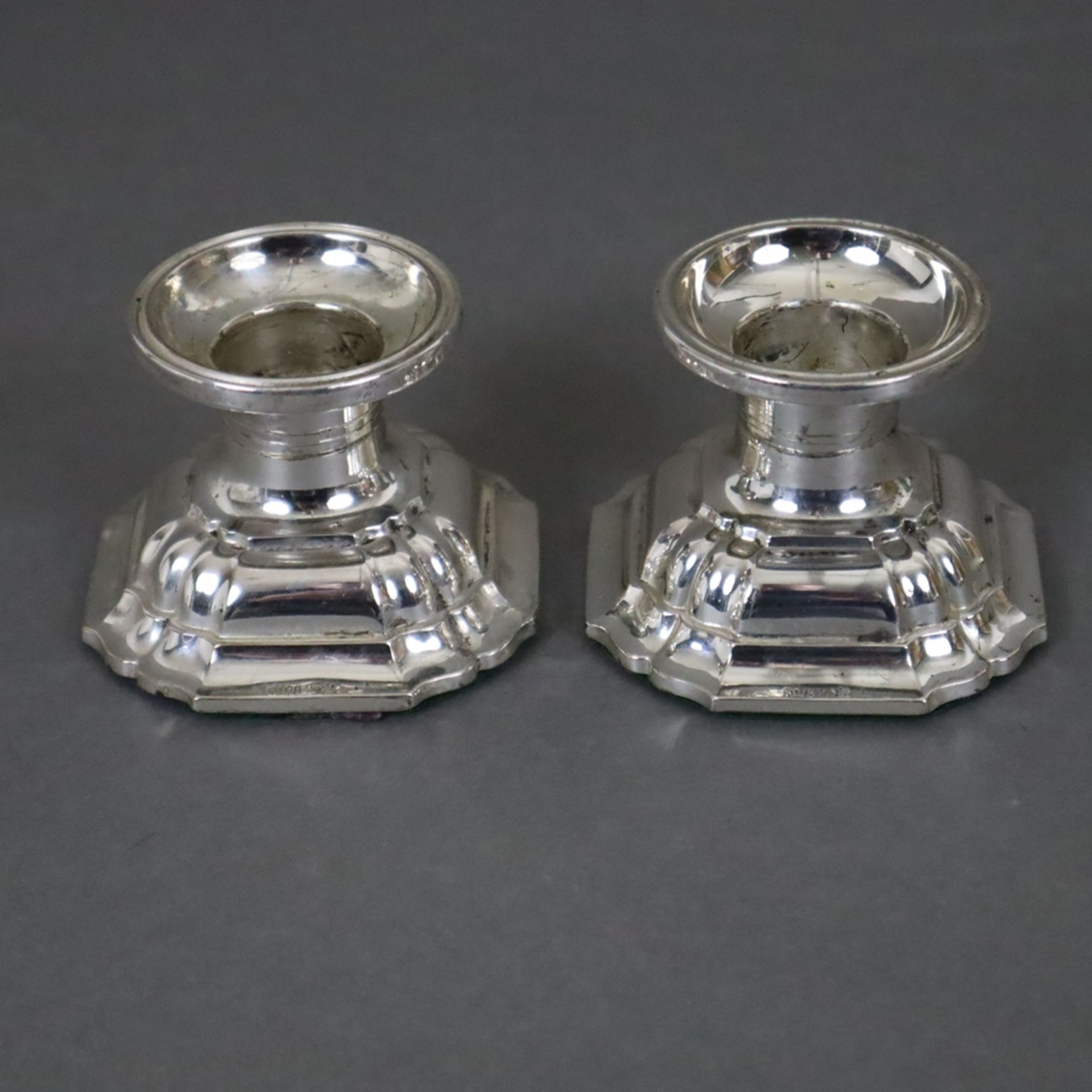 Ein Paar Kerzenleuchter - 835er Silber, runde Tülle, getreppter Stand mit passig eingezogenen Ecken