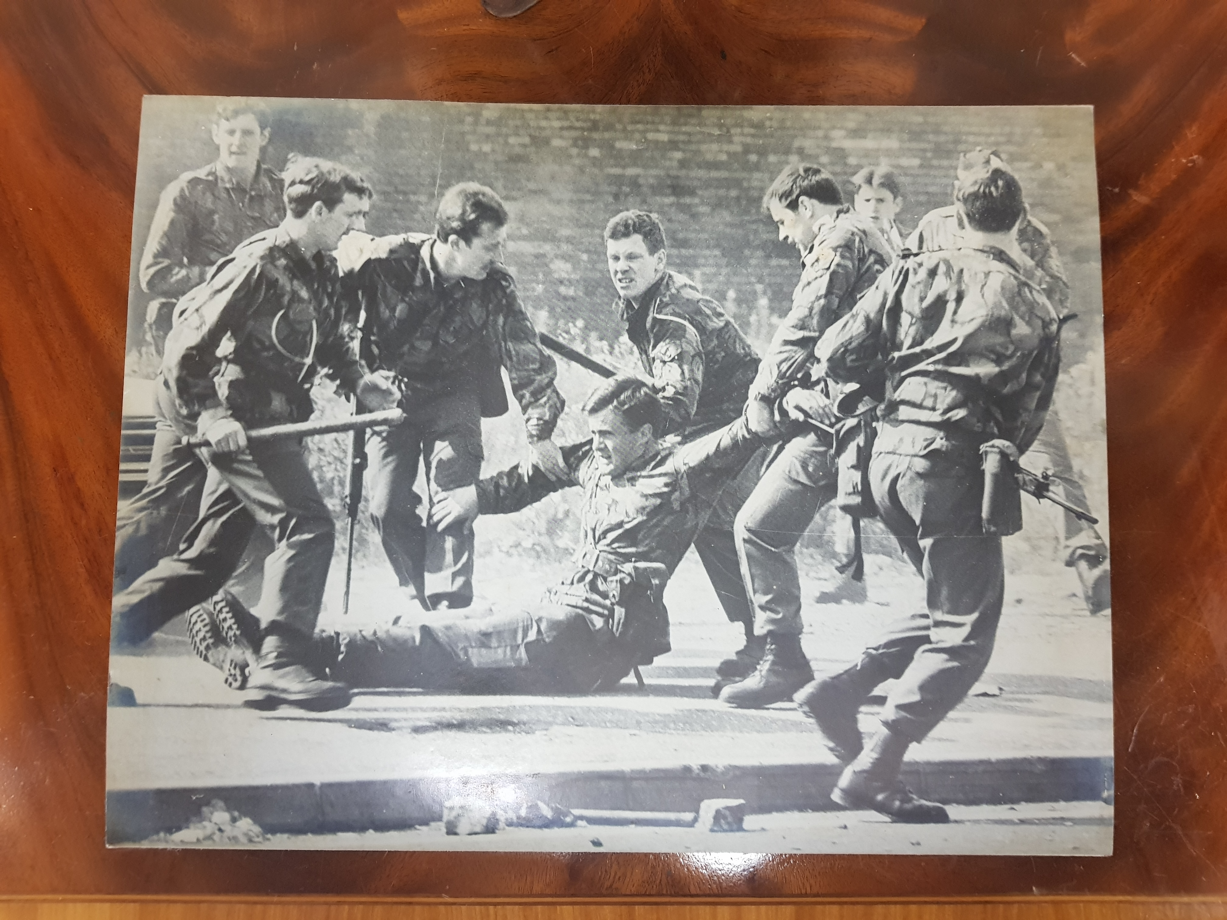 LARGE 1970'S PHOTOGRAPH OF INJURED BRITISH SOLDIER ON LOWER FALLS ROAD