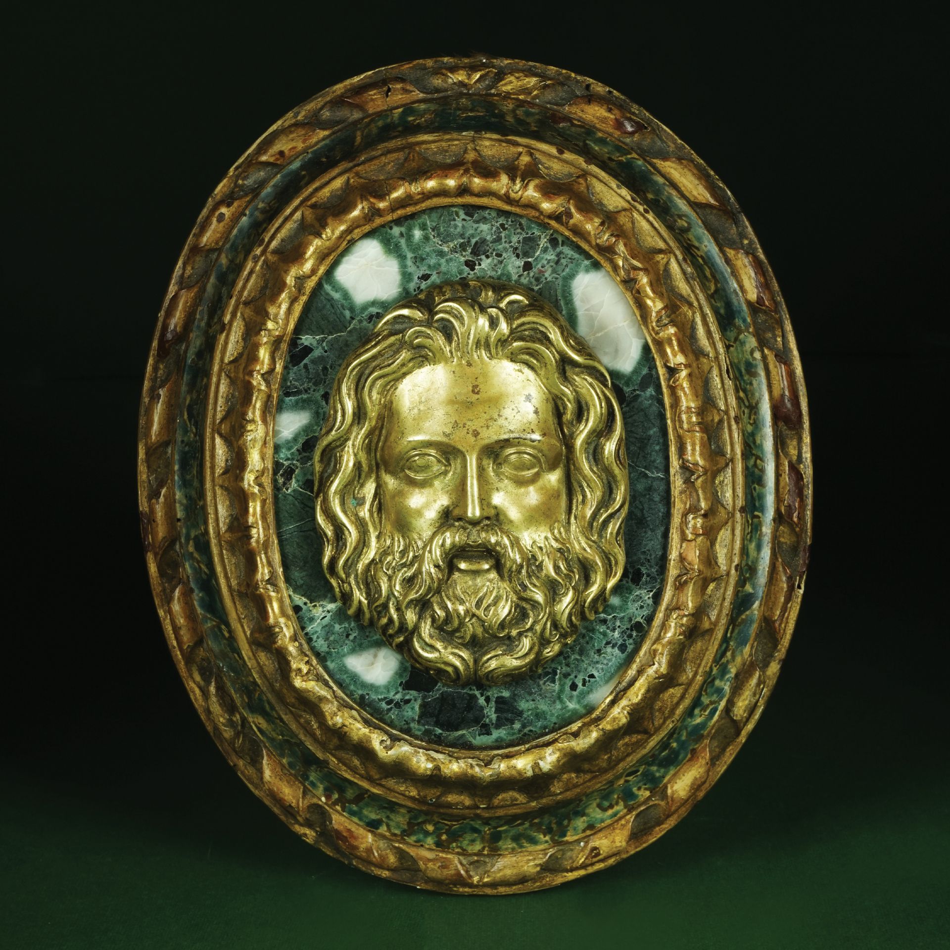 A Roman breccia oval plate decorated with a gilt bronze head of Jupiter, 18th century in a coeval