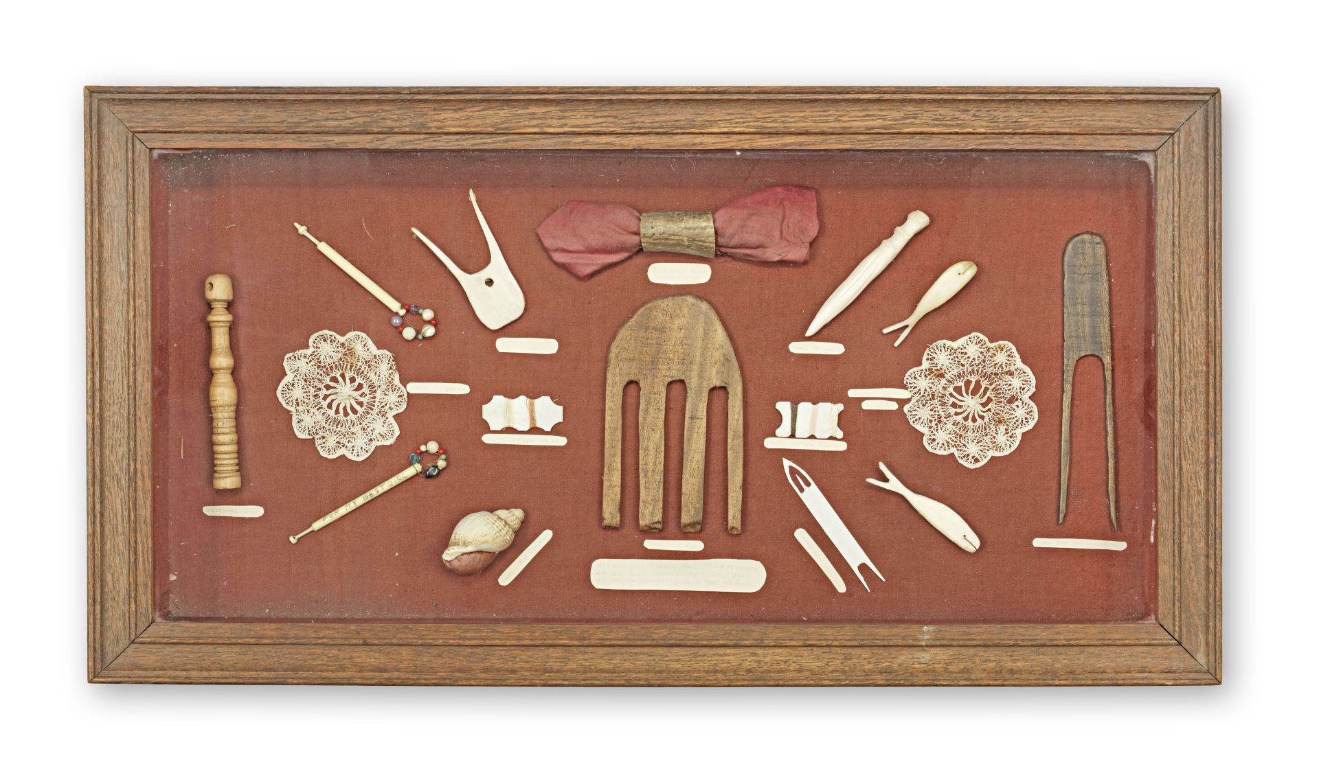 An oak and glass display case enclosing a collection of needlework accessories 20th century