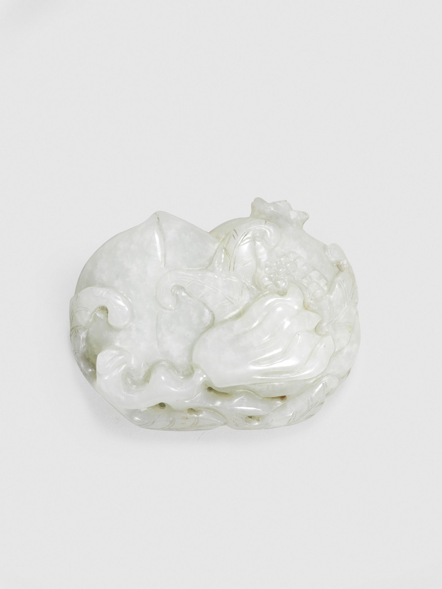 A PALE GREEN JADE 'THREE AUSPICIOUS FRUITS' BELT BUCKLE 18th century