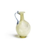 A Roman pale green glass jug with blue looped handle
